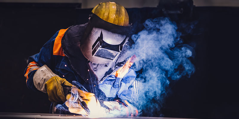 Blue-collar worker welds in a factory.